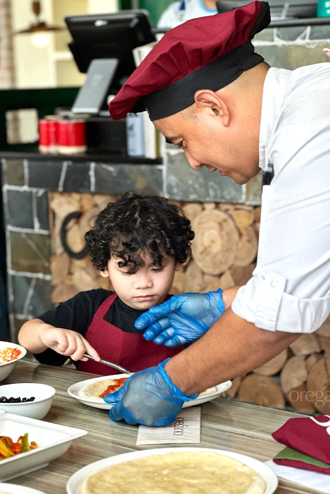Chef helping a child with pizza